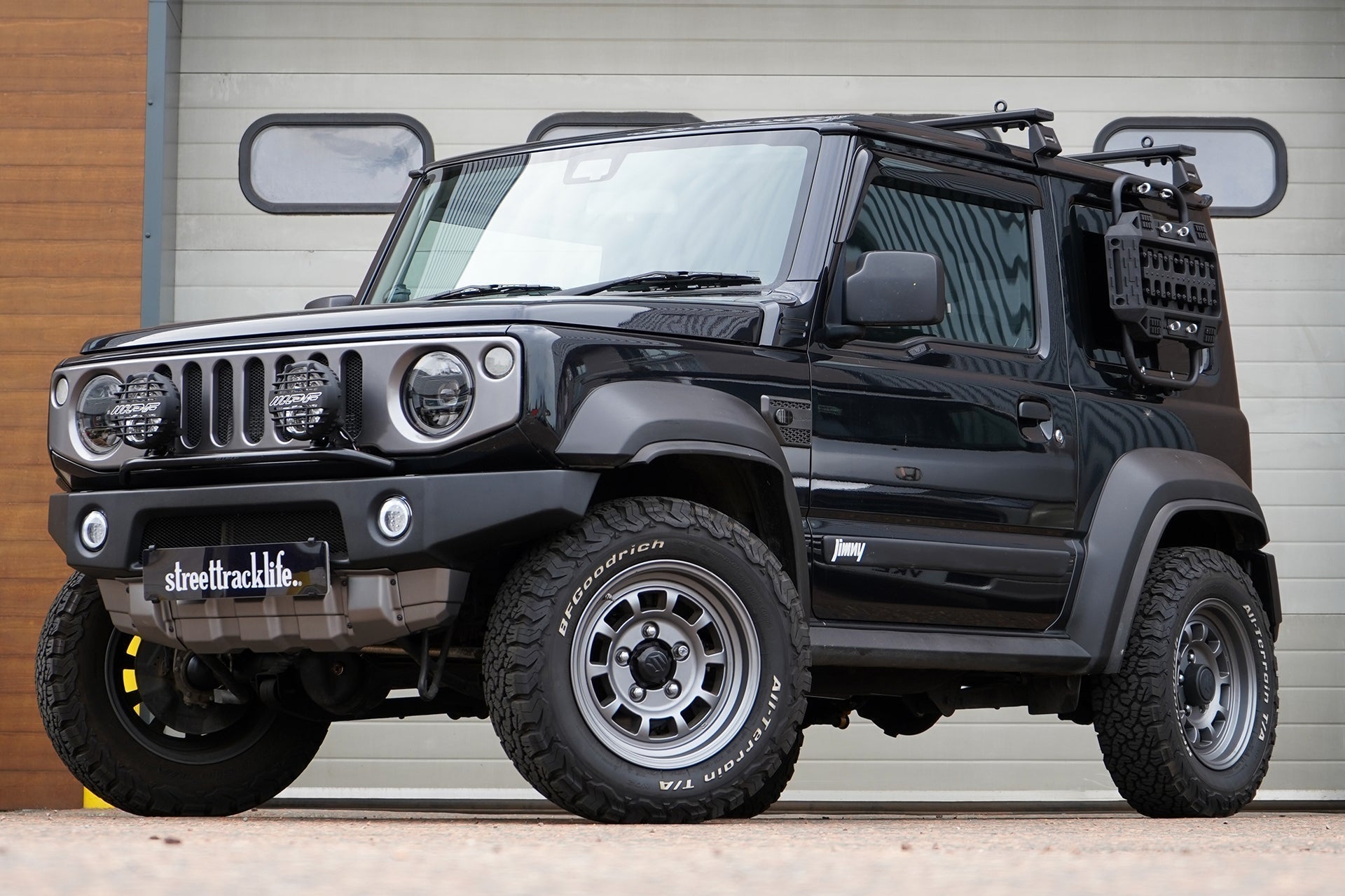 Black Suzuki Jimny (2018+) with APIO Tactical Bumpers (front and rear) and SJ grille. Vehicle is also fitted with 16" HIGH PEAK J-01 wheels in Matte Anthracite and BF Goodrich KO2 tyres